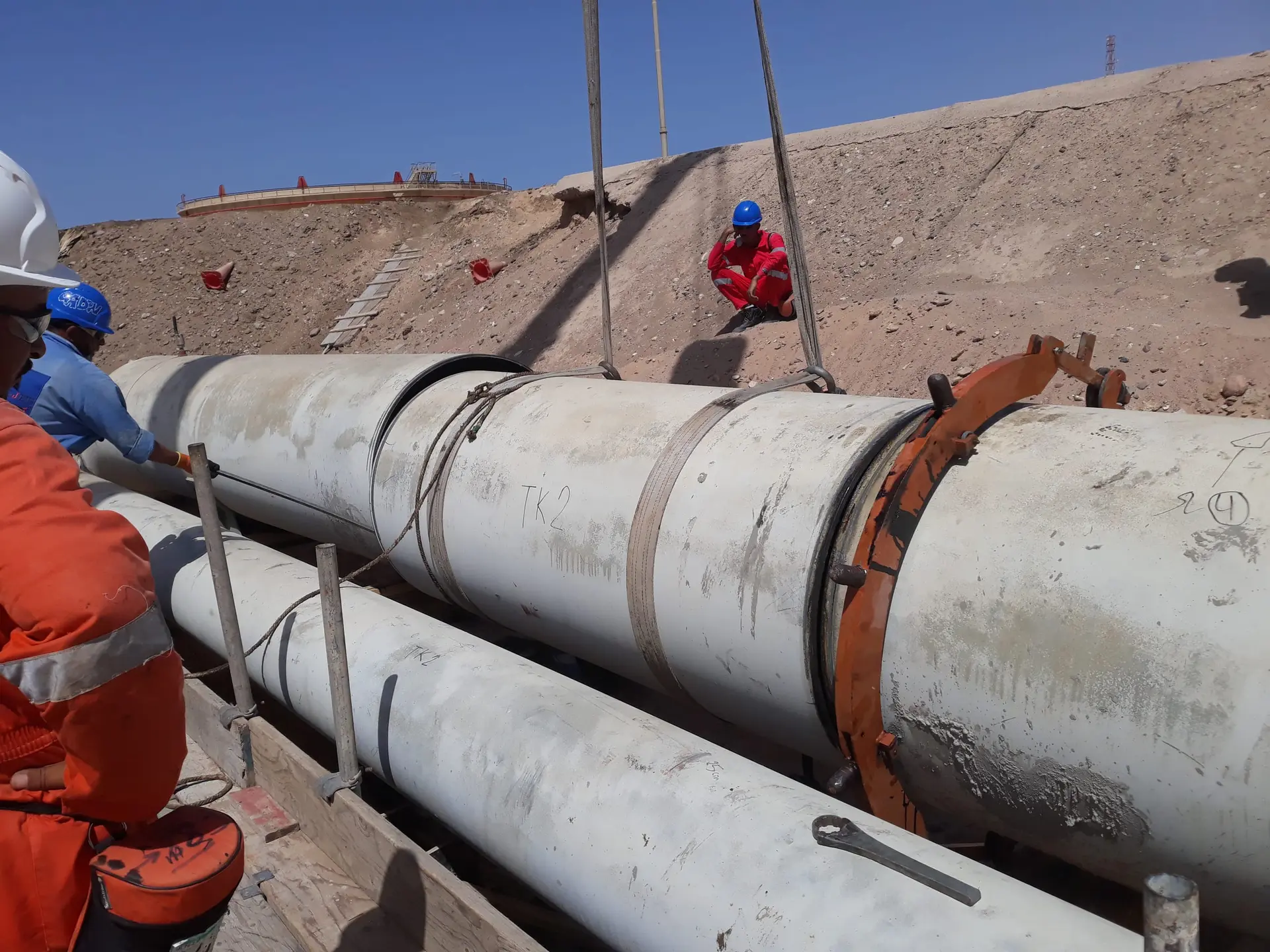 Crew aligning a large-diameter pipe section with a clamp