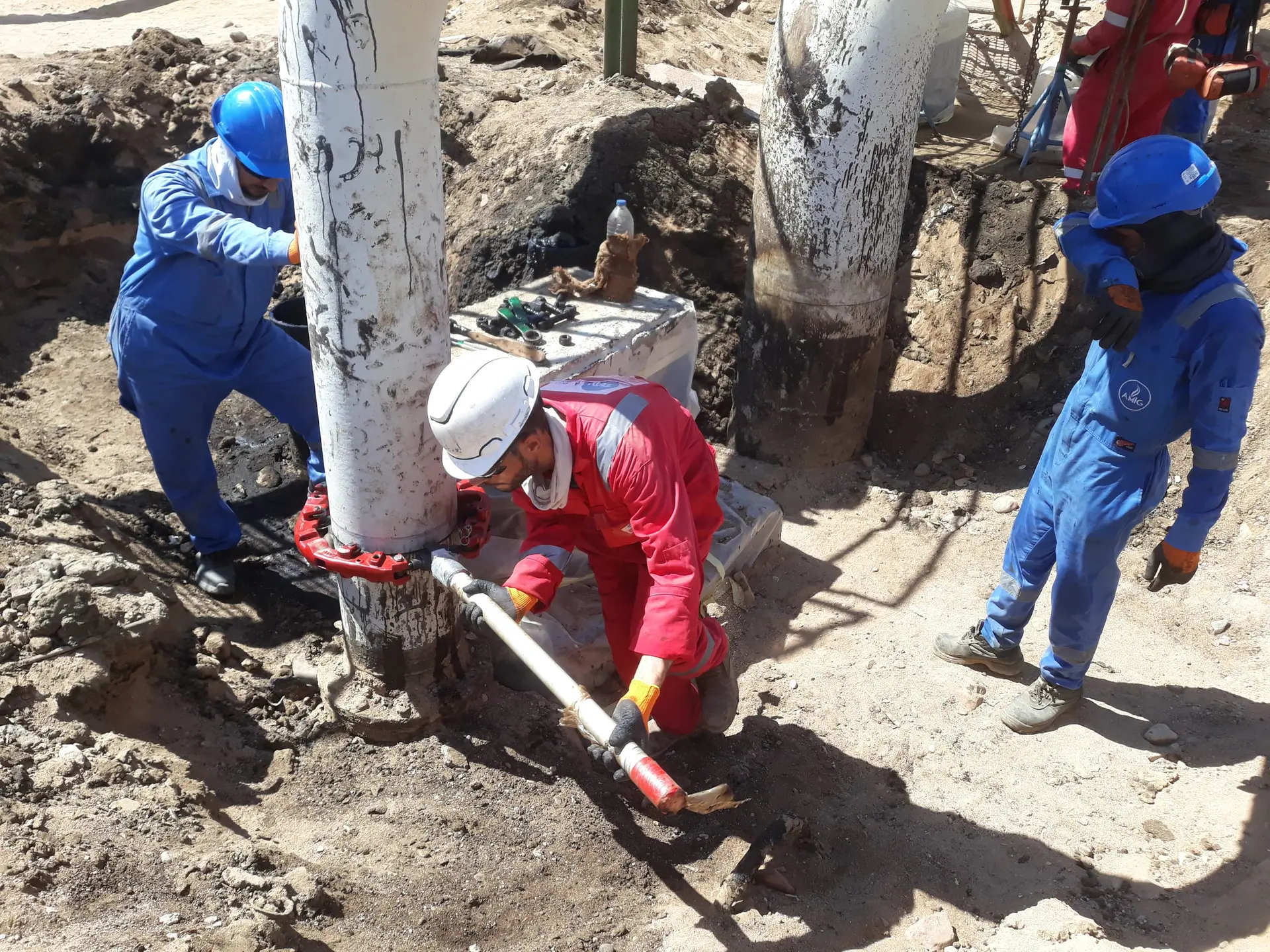 Crew in safety gear working on a pipe in an excavation