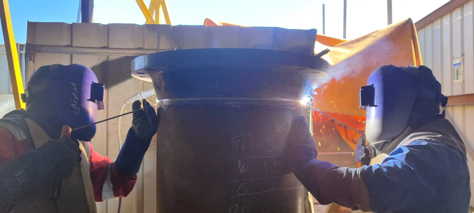 Welders working on a large-diameter pipe joint