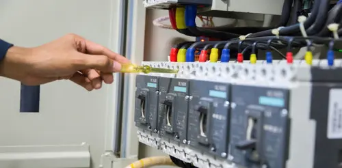 Technician checking wiring in an electrical distribution panel
