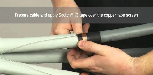 Hands applying tape to a medium-voltage cable during termination